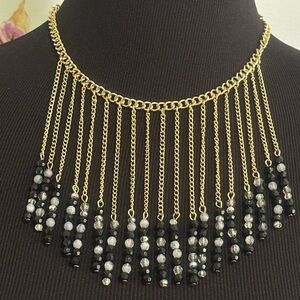 Gold tone beaded, necklace with black,gray, and clear beads.